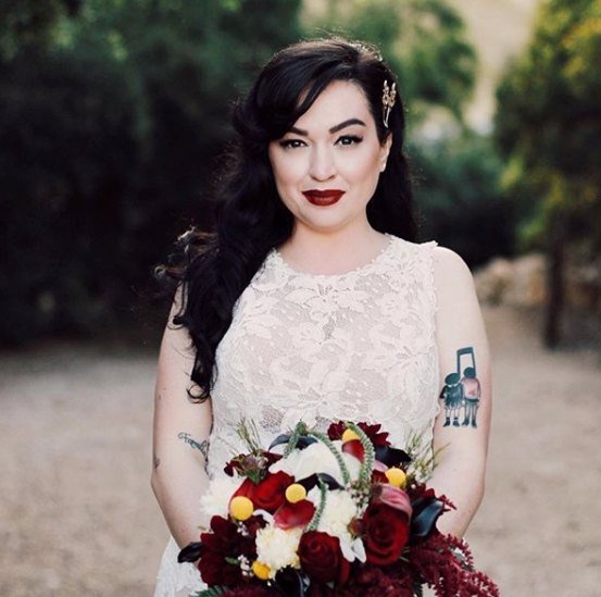 Bride with glossy dark vintage waves and a red bouquet