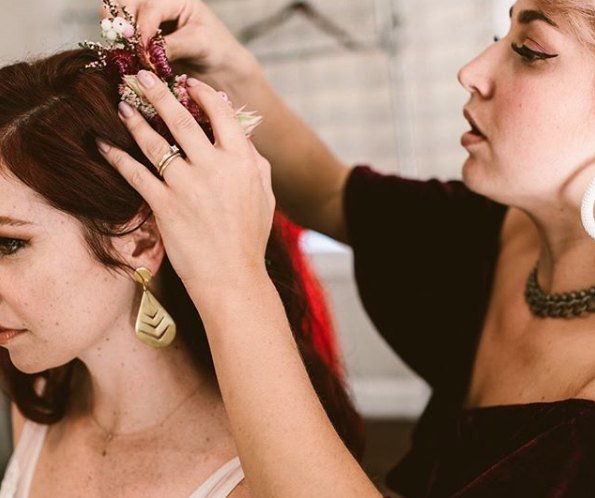 A stylist placing dried flowers into a bridal style