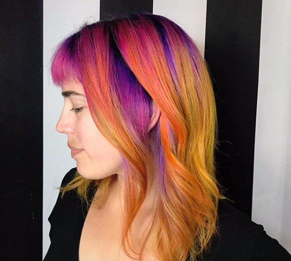 Sunset color melt from violet roots through orange to gold